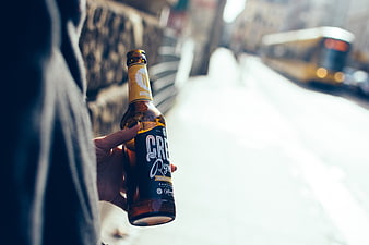 Hand holding beer bottle on snowy city street
