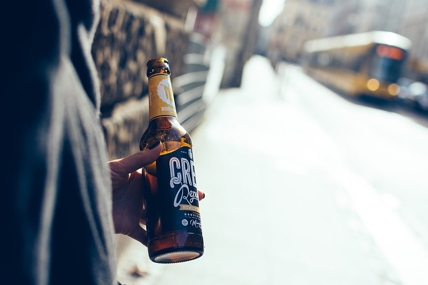 Hand holding beer bottle on snowy city street