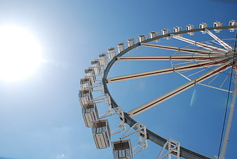 Ferris Wheel Against Blue Sky with Sun Flare