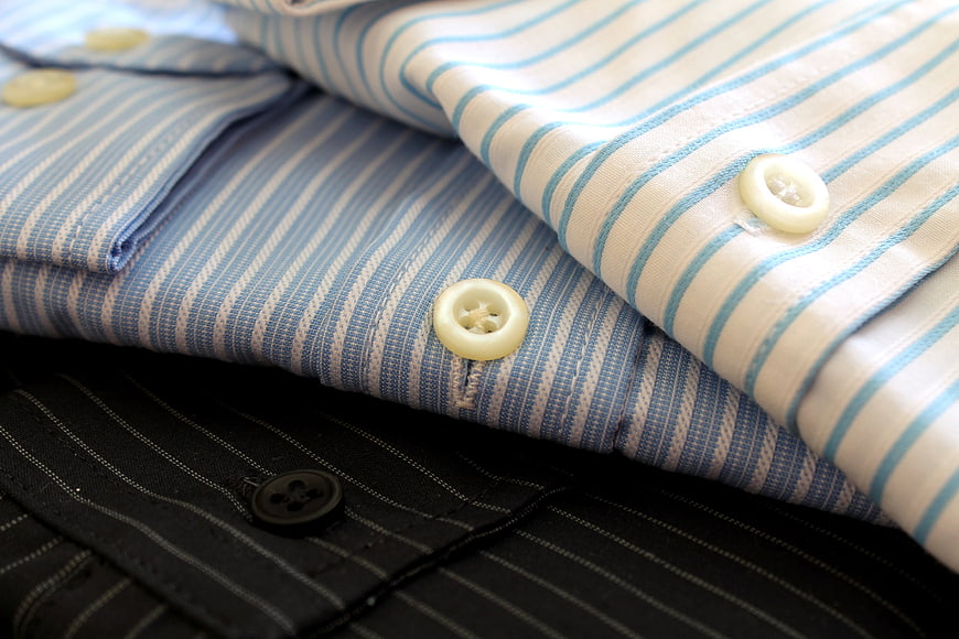 Stack of folded striped dress shirts with close-up buttons