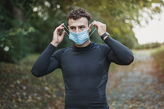 Athletic man putting on face mask outdoors