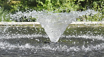 Dynamic water fountain splash with droplets and green background