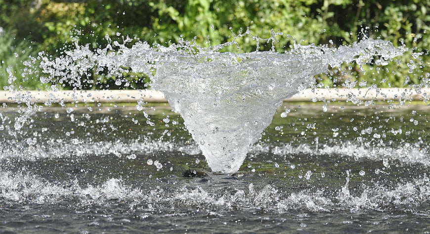 Dynamic water fountain splash with droplets and green background
