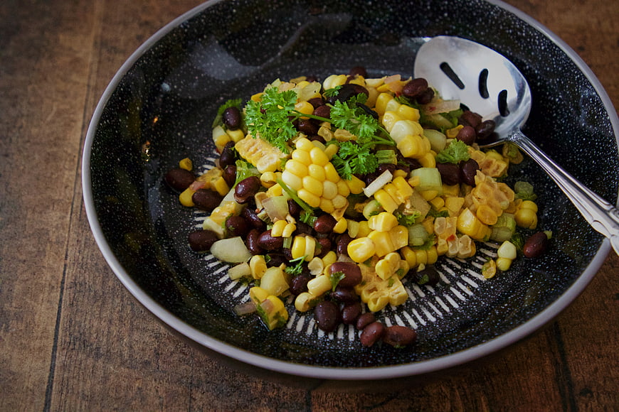 Fresh corn and black bean salad in a dark bowl