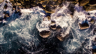 Aerial View of Turbulent Ocean Waves Crashing Against Rocky Coastline