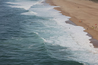 Aerial View of Surfers and Waves on Sandy Beach