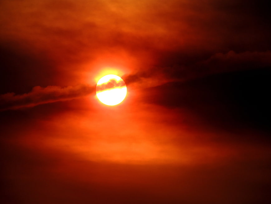 Dramatic red sunset with bright sun and dark clouds
