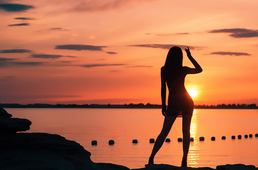 Silhouette of Woman Standing by Lake at Sunset