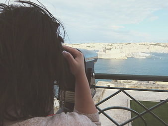 Woman Using Binoculars Overlooking Coastal Harbor City