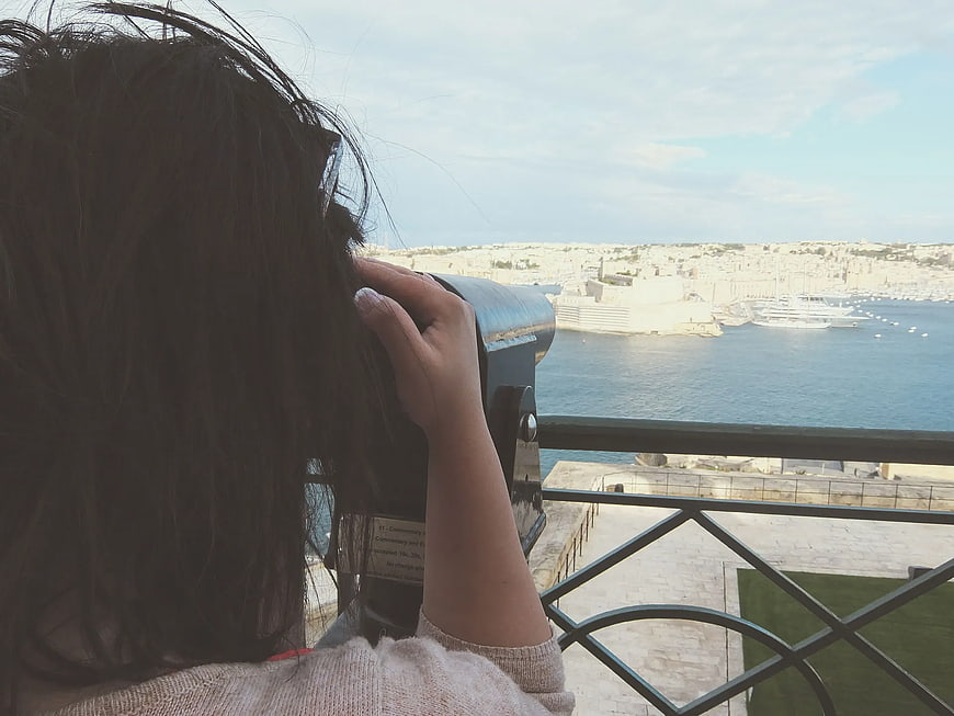 Woman Using Binoculars Overlooking Coastal Harbor City
