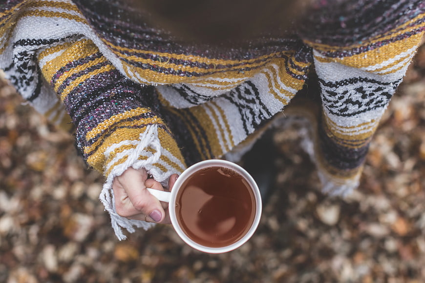 Person holding coffee cup in cozy knit sweater