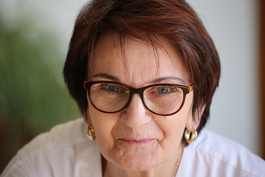 Close-up portrait of senior woman with glasses and warm smile