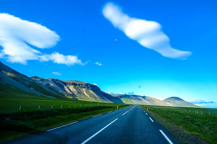 Scenic asphalt road through green highlands under blue sky