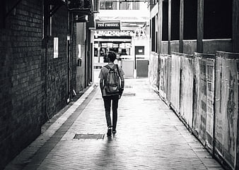 Man with Backpack Walking Down Urban Alleyway