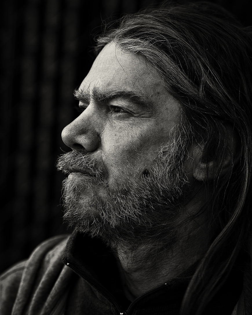 Black and white profile portrait of a bearded man with long hair