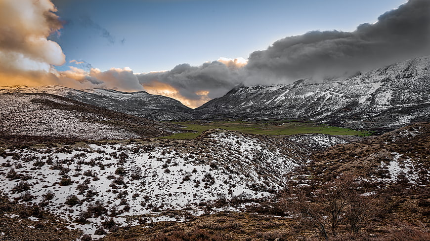 Dramatic Snow-Capped Mountain Valley with Golden Sunset Clouds