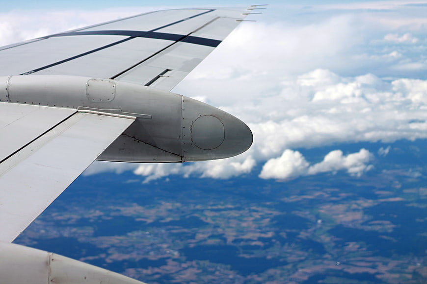 Airplane Wing View Over Clouds and Landscape
