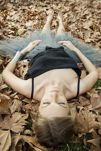 Woman in black dress lying on autumn leaves