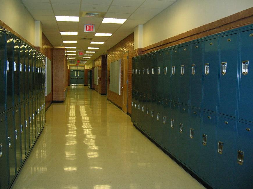 Empty school hallway with blue lockers and shiny floor