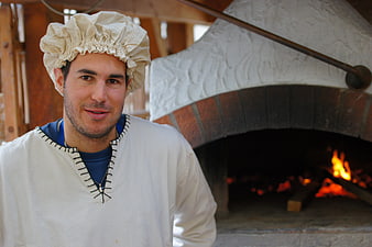 Man in Traditional Costume Standing by Wood-Fired Oven
