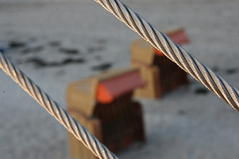 Close-up of twisted steel cables on a sandy beach background