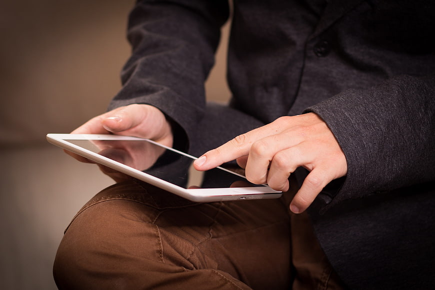 Close-up of hands using a white tablet computer