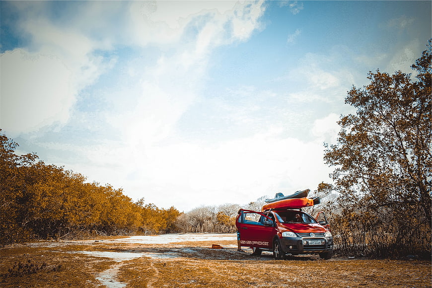 Red SUV with Kayak on Roof in Snowy Forest