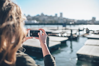 Woman Taking Photo of Cityscape with Smartphone by Water