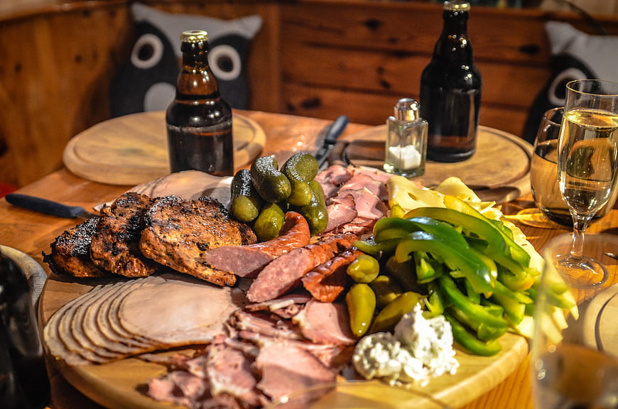 Rustic charcuterie board with meats, pickles, and beer