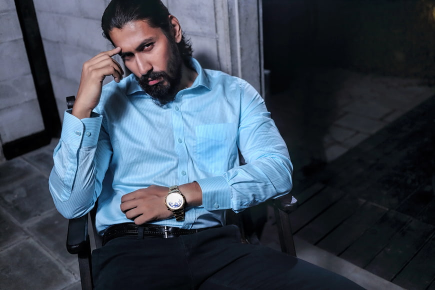 Thoughtful Bearded Man in Blue Shirt Sitting in Armchair