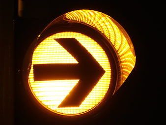 Close-up of glowing yellow traffic light arrow pointing right