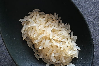 Uncooked white rice grains in a black spoon