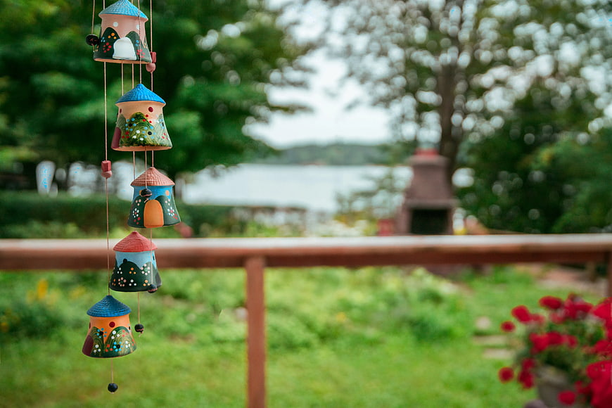 Colorful ceramic wind chimes hanging on a porch railing