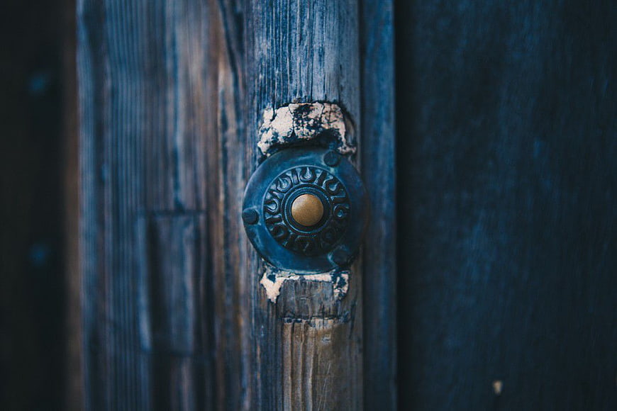 Close-up of vintage doorbell on weathered blue wooden door