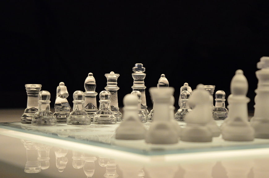 Glass Chess Set on Reflective Board with Black Background
