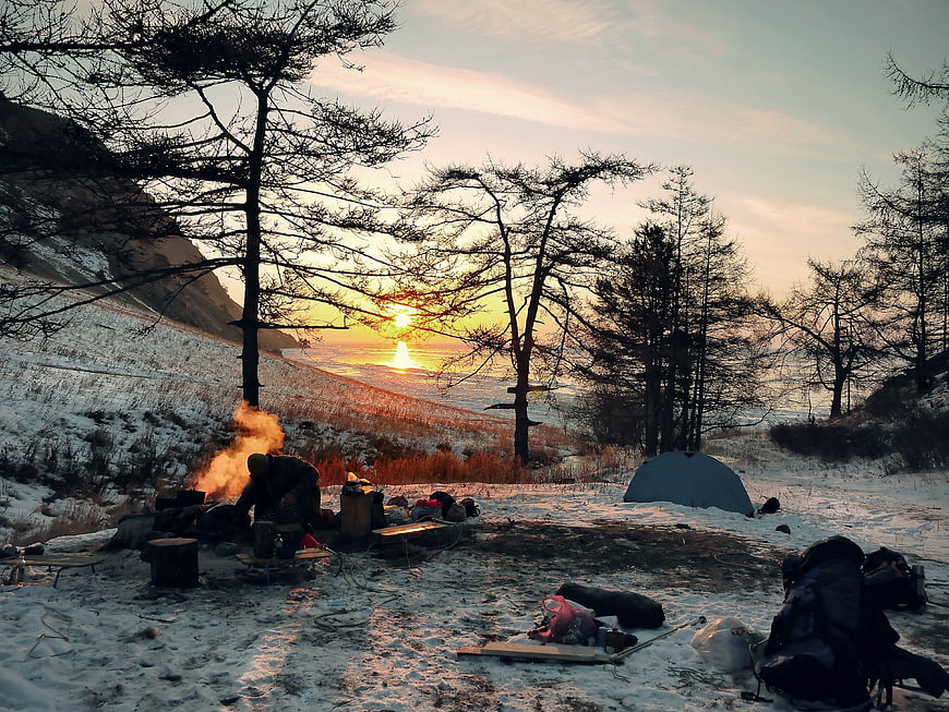 Winter Camping Scene With Campfire And Tent At Sunset
