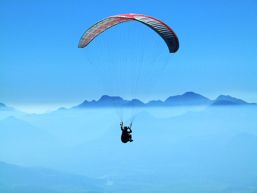 Paraglider soaring above misty mountain layers