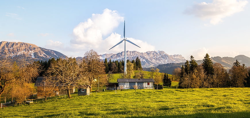 Wind Turbine in Green Meadow with Mountain Range Background