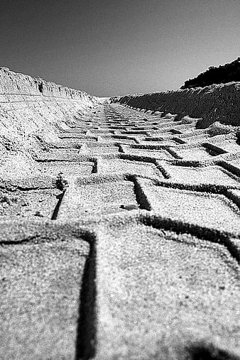 Black and white photo of tire tracks in sand