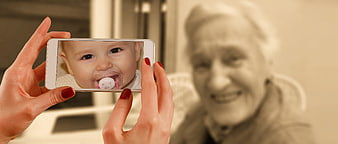 Senior woman video calling baby on smartphone screen