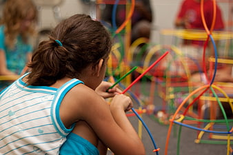 Young girl building colorful structure with sticks