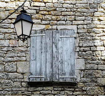 Rustic stone wall with weathered wooden shutters and lantern