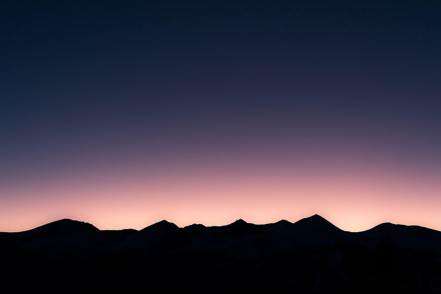 Silhouette of mountain range against twilight gradient sky