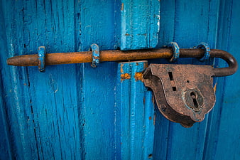 Rusty Padlock on Weathered Blue Wooden Door