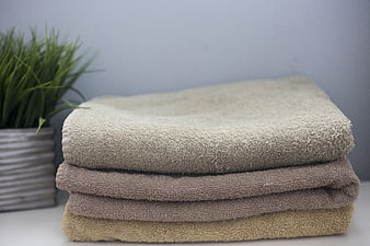 Stacked beige and brown cotton towels with potted plant