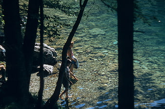 Woman and child wading in clear shallow river stream