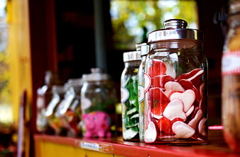 Glass jars filled with heart-shaped candies on a wooden shelf