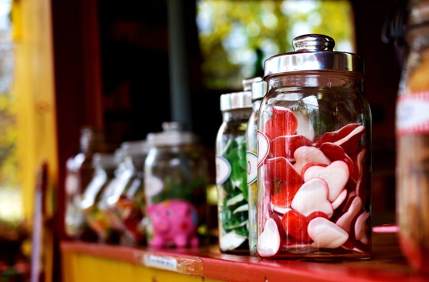 Glass jars filled with heart-shaped candies on a wooden shelf