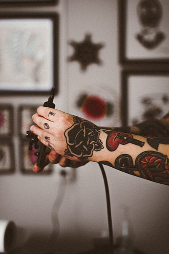 Tattooed Hand Holding Tattoo Machine in Studio