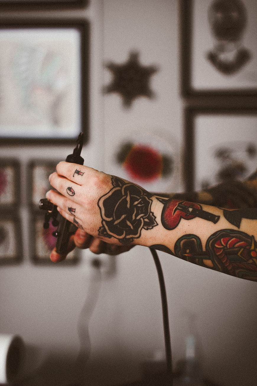 Tattooed Hand Holding Tattoo Machine in Studio